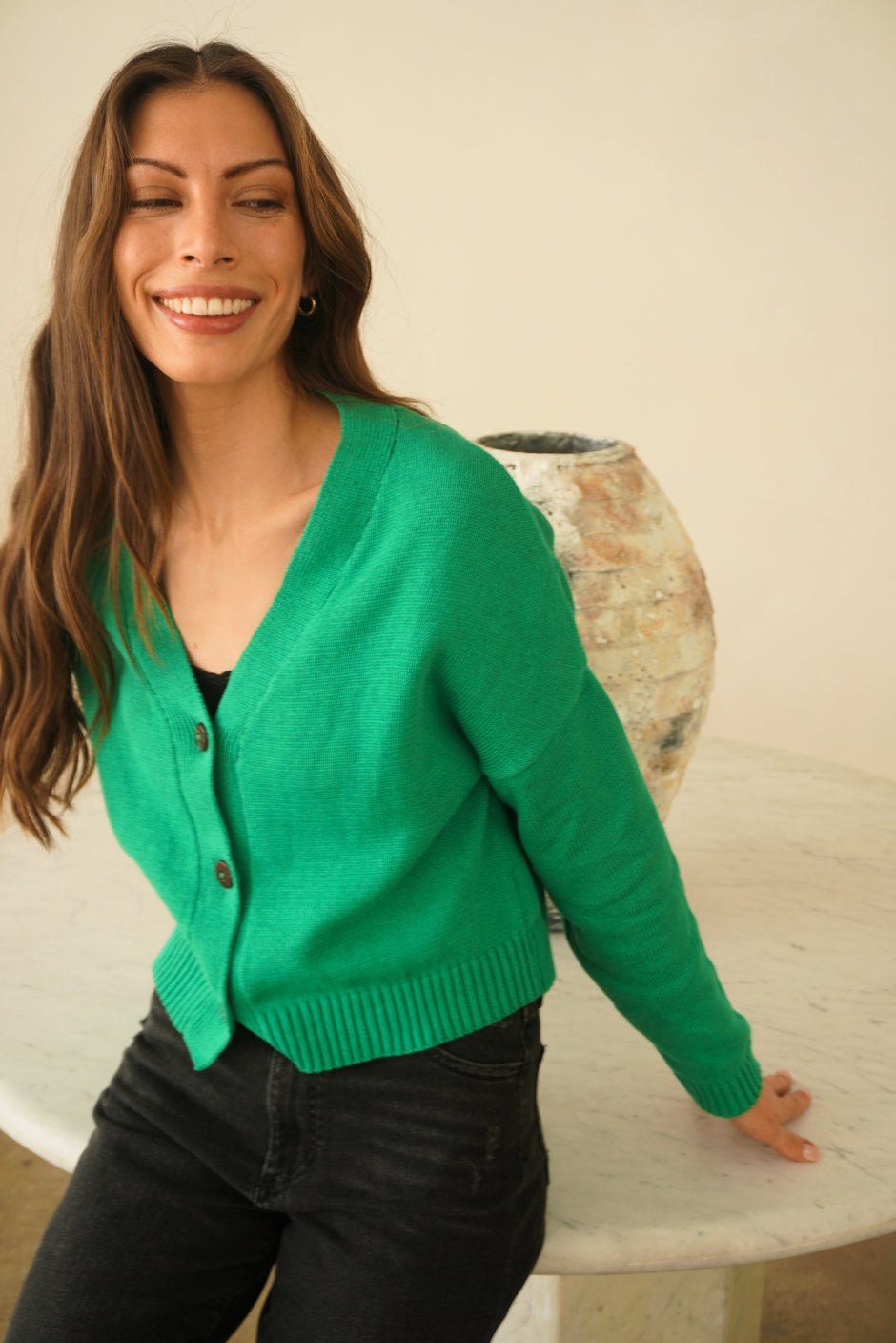 Emerald Green sustainable cropped-length Cotton Diana Cardigan from Paneros Clothing with real coconut shell button-up front, Full sleeves, and feminine handknittting. Front/Side View buttoned.