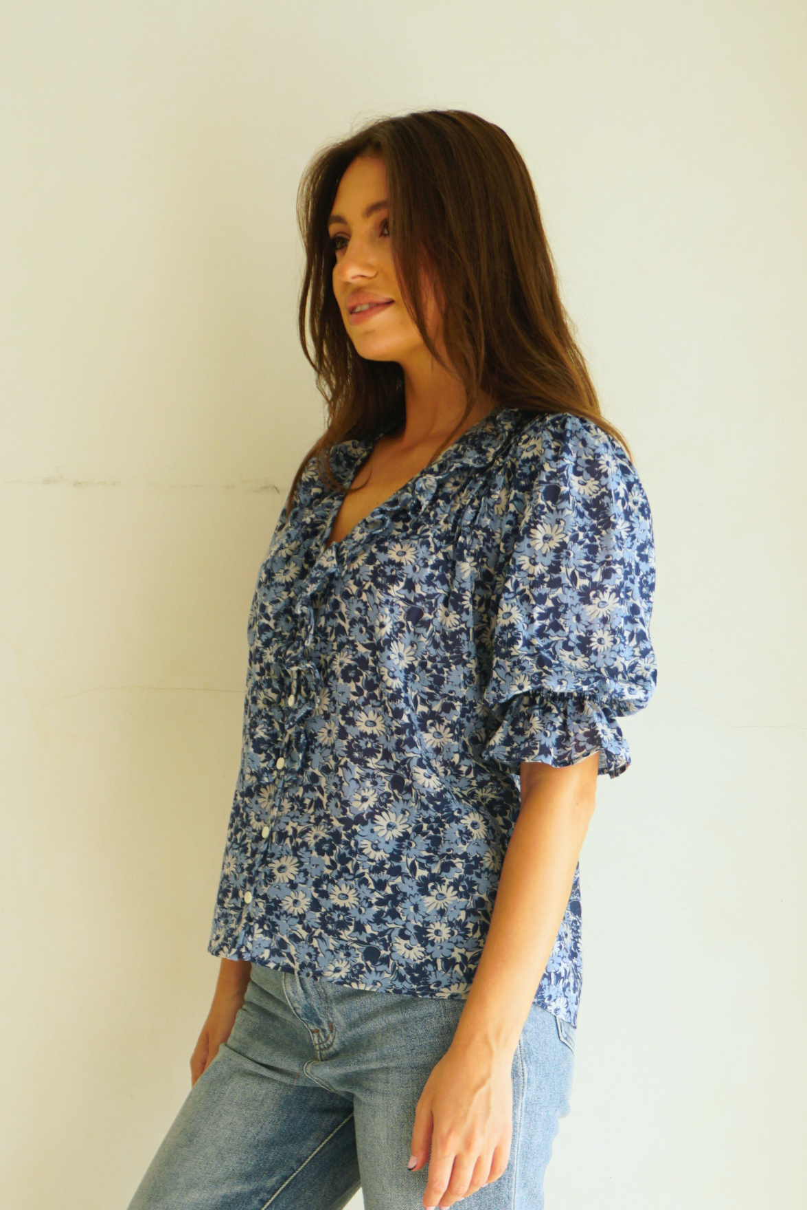 Blue Floral Spring/Summer Chloe Shirt from Paneros Clothing with button-up front and Elbow-length sleeves and ruffles. Sustainable cotton fully-lined top with smocking. Side View.