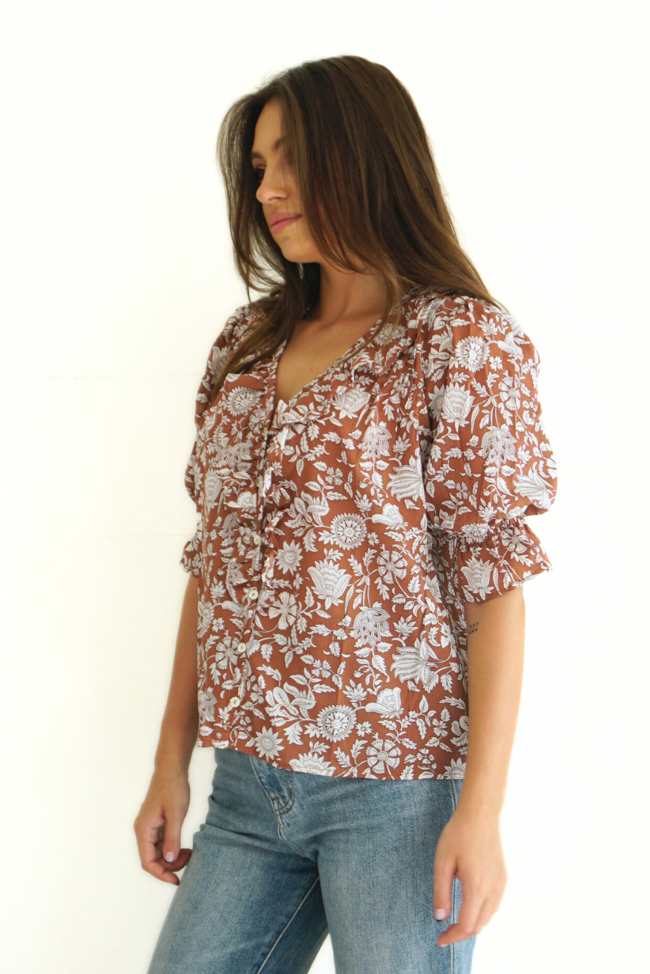 Brown Floral Spring/Summer Chloe Shirt from Paneros Clothing with button-up front and Elbow-length sleeves and ruffles. Sustainable cotton fully-lined top with smocking. Side View untucked.