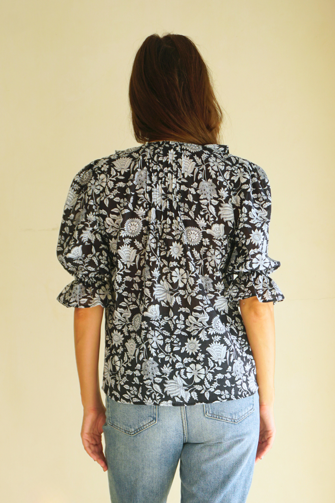 Black Floral Spring/Summer Chloe Shirt from Paneros Clothing with button-up front and Elbow-length sleeves and ruffles. Sustainable cotton fully-lined top with smocking. Back View.