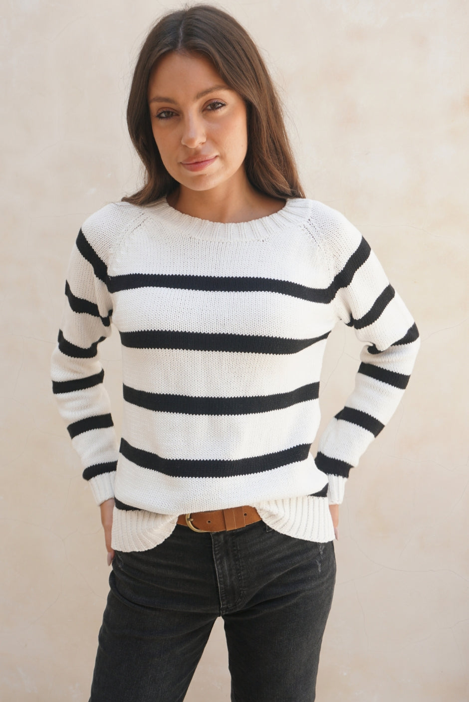 Black and White Striped sustainable cotton handknitted Sloane Crewneck by Paneros Clothing. Relaxed-fit hip-length crewneck sweater with long sleeves and ribbing details. Front View tucked into denim.