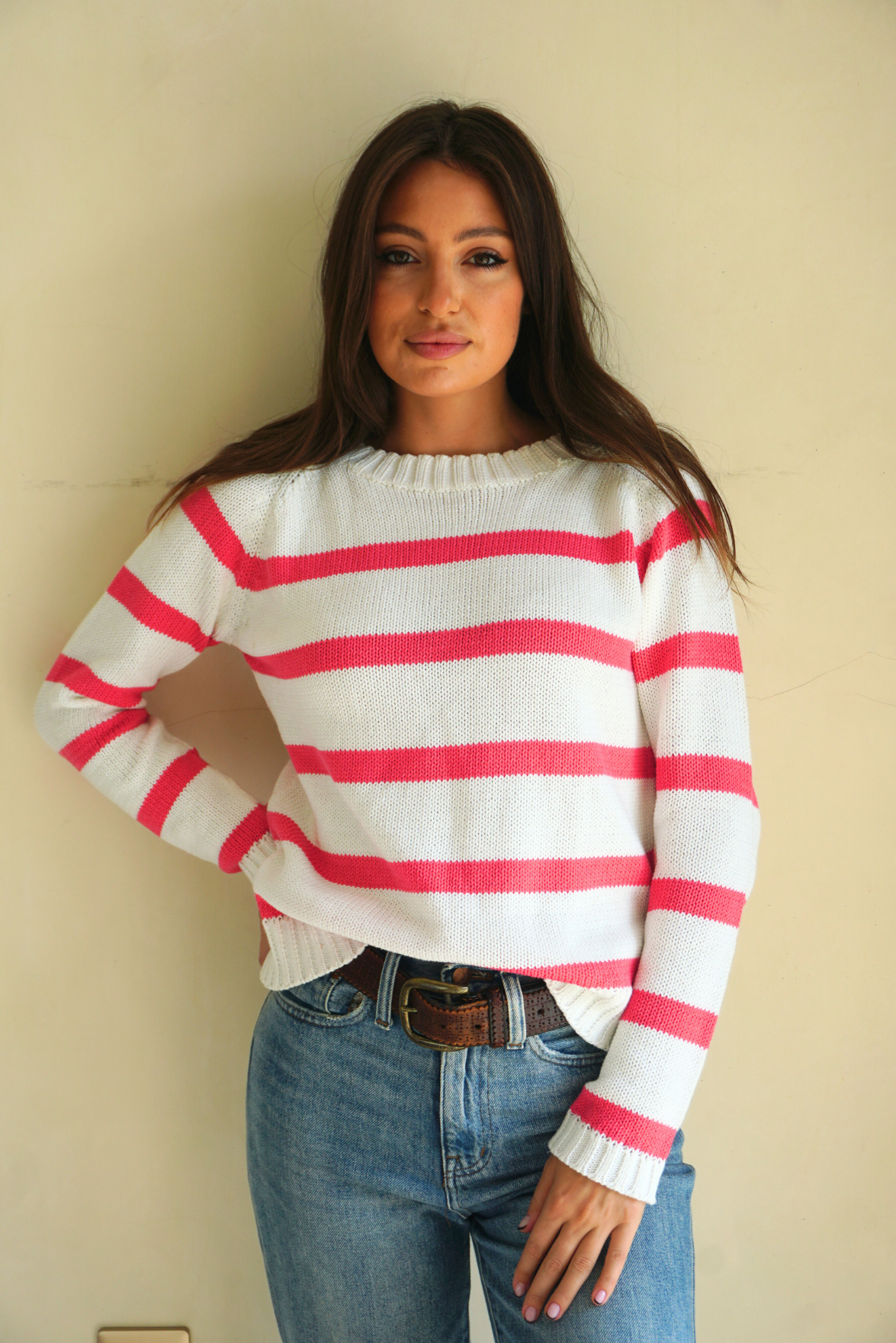 Hot Pink and White Striped sustainable cotton handknitted Sloane Crewneck by Paneros Clothing. Relaxed-fit hip-length crewneck sweater with long sleeves and ribbing details. Front View tucked into denim.