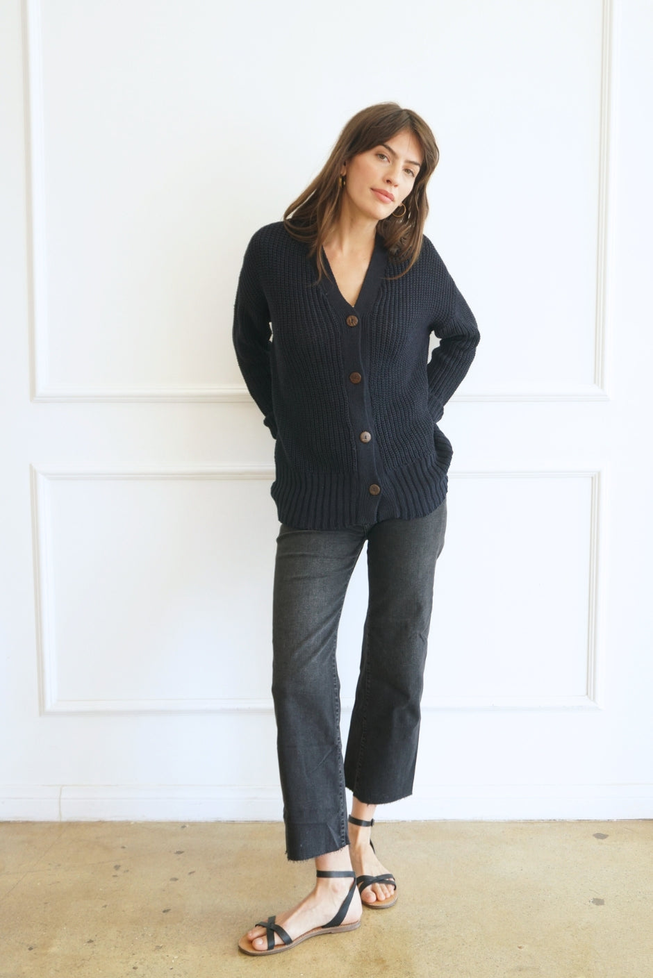 Dark Navy Blue Sustainable Cotton Hip-Length Button-up Emily Cardigan by Paneros Clothing. Hand-knitted, slightly oversized cardigan with real coconut shell buttons and ribbed detailing. Front View buttoned.