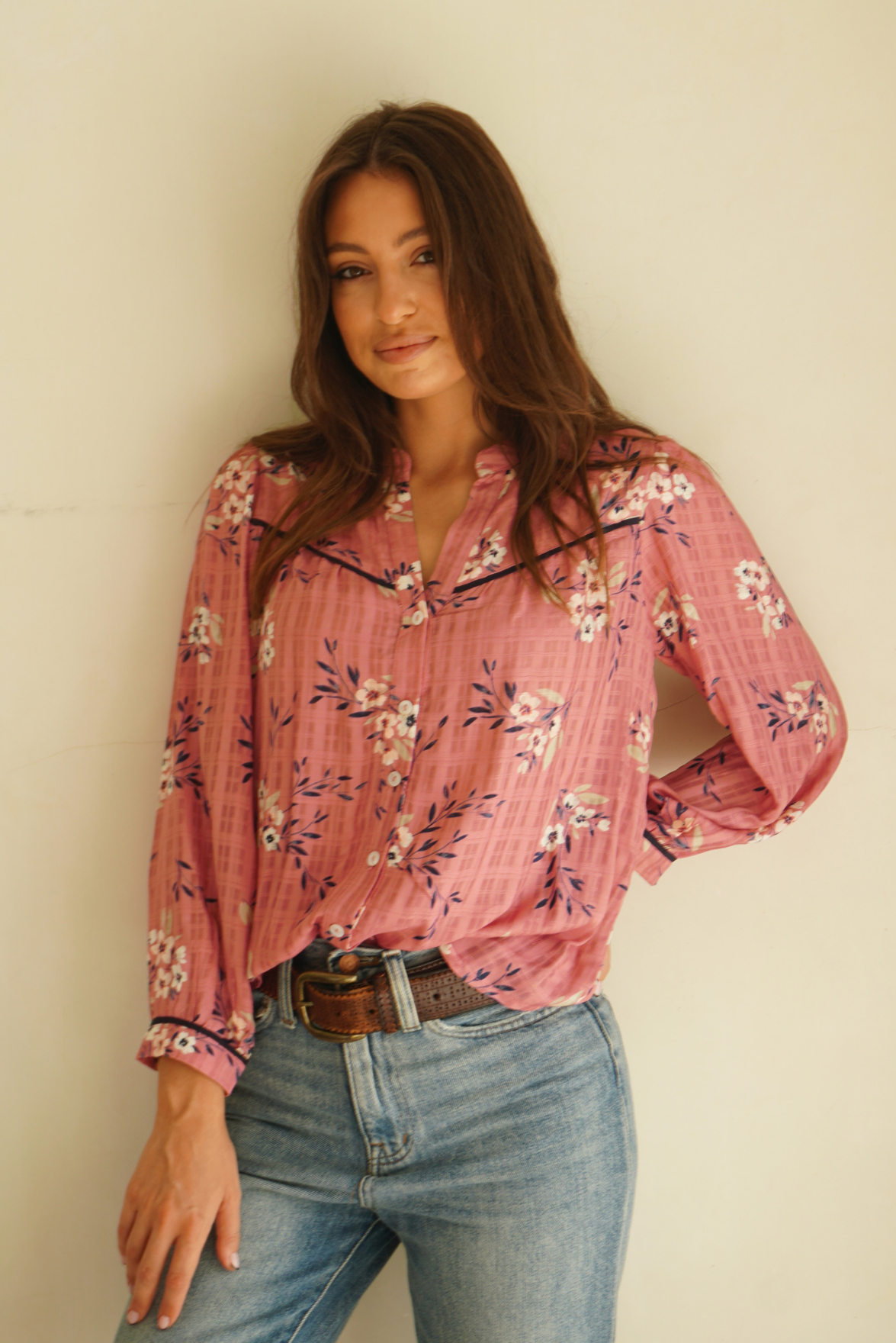 Pink Floral Print Anna Shirt from Paneros Clothing with button-up front and long sleeves. Sustainable rayon dobby shirt blouse in pink floral print with contrast navy piping details. Front View tucked into denim.