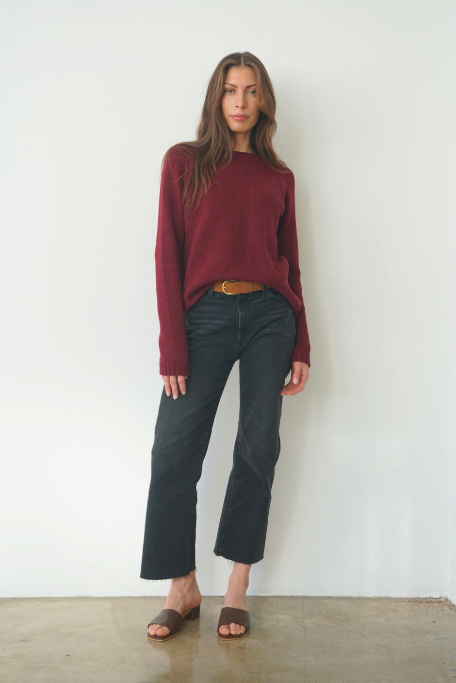 Burgundy sustainable cotton handknitted Sloane Crewneck by Paneros Clothing. Relaxed-fit hip-length crewneck sweater with long sleeves and ribbing details. Front View tucked into denim.