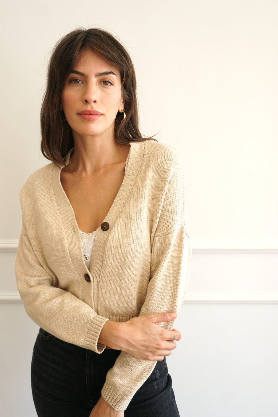 Tan sustainable cropped-length Cotton Diana Cardigan from Paneros Clothing with real coconut shell button-up front, Full sleeves, and feminine handknittting. Front View half-buttoned.