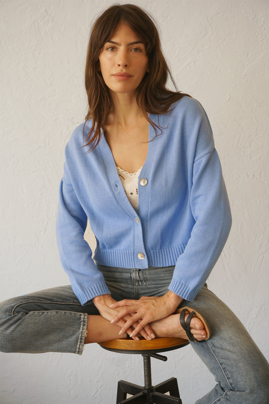 Baby Blue sustainable cropped-length Cotton Diana Cardigan from Paneros Clothing with real coconut shell button-up front, Full sleeves, and feminine handknittting. Front View half-buttoned.