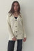 Creamy Off-White Sustainable Cotton Hip-Length Button-up Emily Cardigan by Paneros Clothing. Hand-knitted, slightly oversized cardigan with real coconut shell buttons and ribbed detailing. Detailed Full Body View in motion, buttoned.