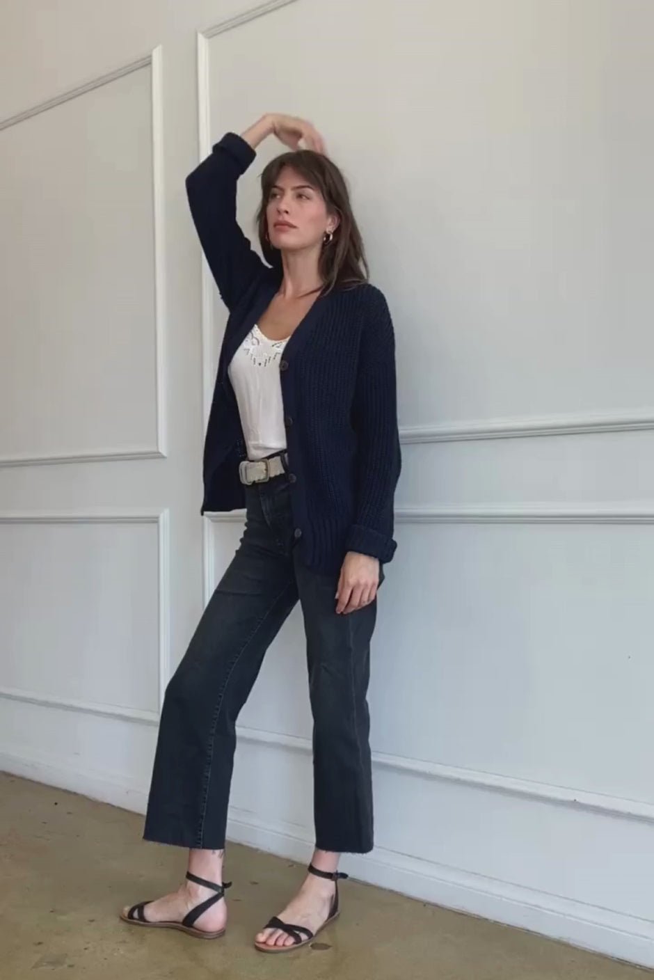 Dark Navy Blue Sustainable Cotton Hip-Length Button-up Emily Cardigan by Paneros Clothing. Hand-knitted, slightly oversized cardigan with real coconut shell buttons and ribbed detailing. Side/Back View in motion, unbuttoned.