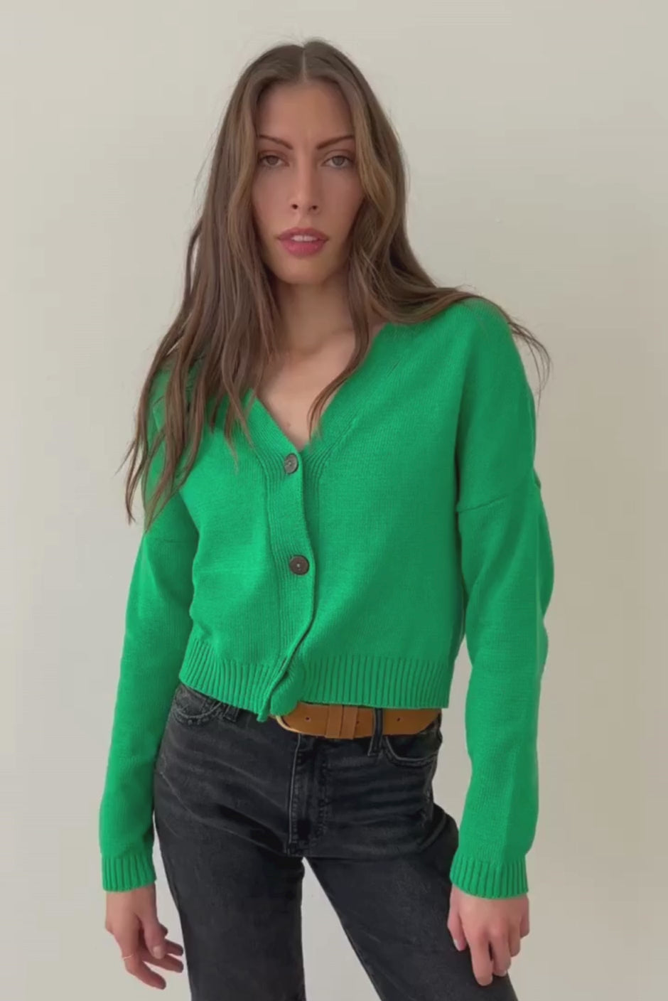 Emerald Green sustainable cropped-length Cotton Diana Cardigan from Paneros Clothing with real coconut shell button-up front, Full sleeves, and feminine handknittting. Full Body View in motion, buttoned.