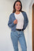 Denim Blue sustainable cropped-length Cotton Diana Cardigan from Paneros Clothing with real coconut shell button-up front, Full sleeves, and feminine handknittting. Front View in motion, unbuttoned.