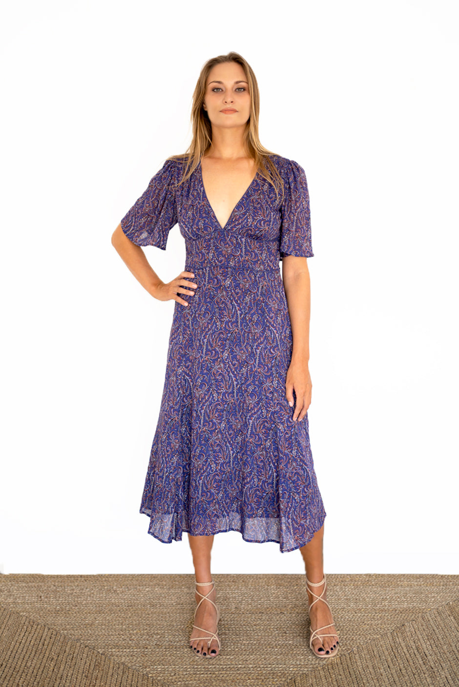 Purple Boho Print Spring/Summer 2022 Aurora Midi Dress from Paneros Clothing with V-neckline and mid sleeves and Piping detail. Front View zoomed out with hands on hip styling.