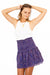 Purple Bohemian Floral Paisley Print Spring/Summer 2022 Lennon Smocked Mini Skirt from Paneros Clothing styled with white tank top. Front View.