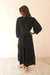 Black Crochet 3/4 Sleeve Women's Maya Below-the-knee Midi Dress from Paneros Clothing with 100% certified sustainable fabric, embroidery, and smocking. Back View.