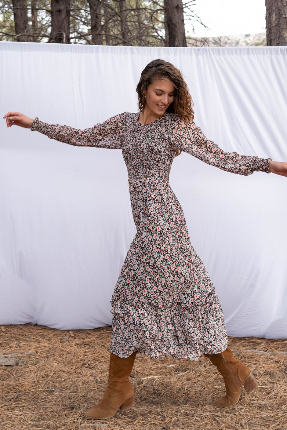 Stella Midi dress in tossed ditsy floral print for women by Paneros Clothing. From sustainable deadstock silk fabric, with smocking ruffles and sleeves. Front walking view.