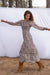Stella Midi dress in tossed ditsy floral print for women by Paneros Clothing. From sustainable deadstock silk fabric, with smocking ruffles and sleeves. Front walking view.